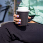 lady holding black takeaway coffee cup